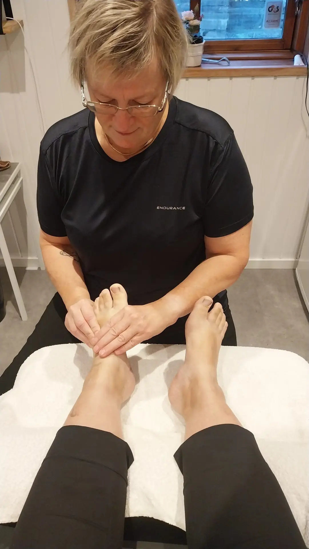 Person får fysiurgisk fodmassage, hvor massøren arbejder med muskler og led i fødderne for at løsne spændinger og forbedre blodcirkulationen.